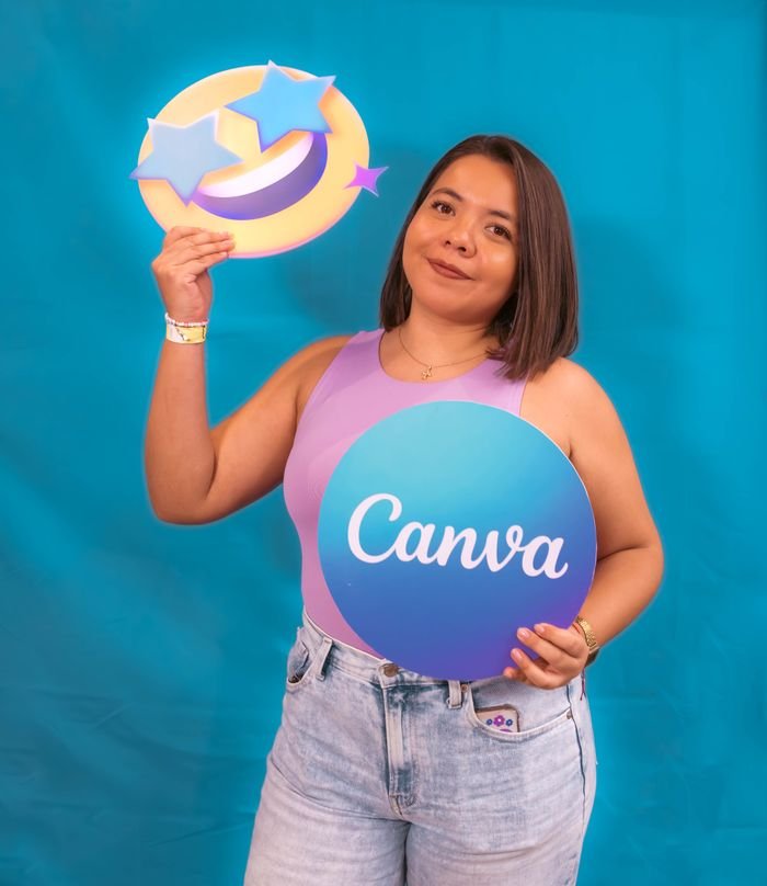 Services Portrait of a young woman holding Canva logo and emoji on a blue background.